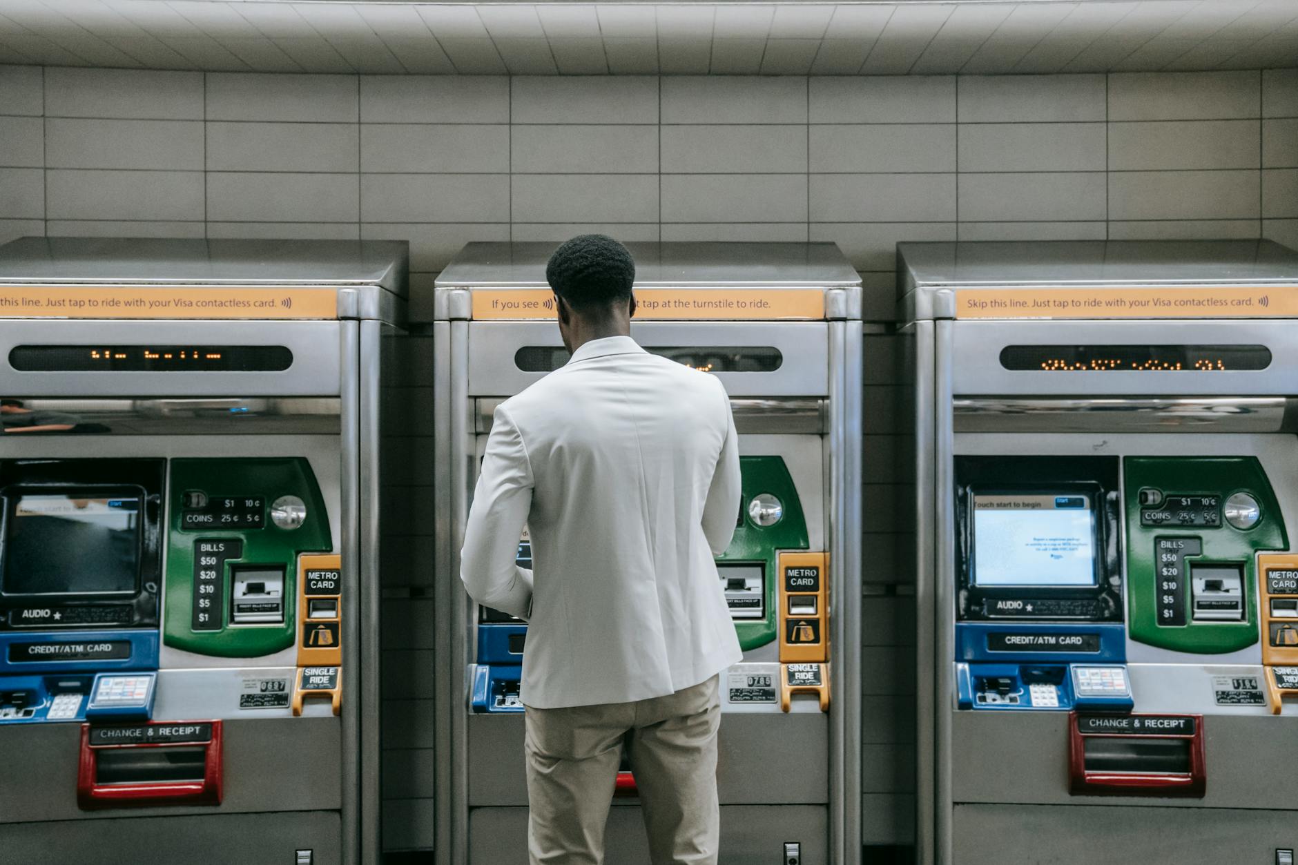 Business professional using a metro ticket machine at a transit station.
