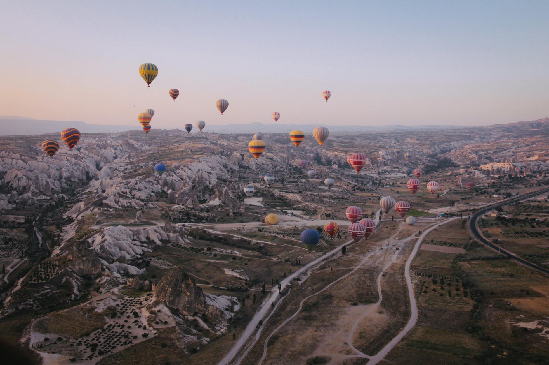 Hot air balloons floating over Cappadocia's unique landscape at sunrise.